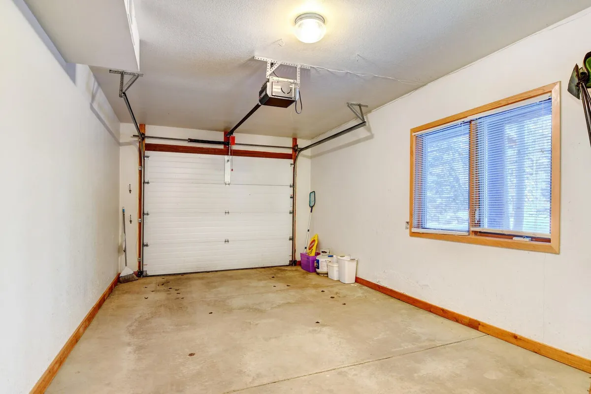 A clean, organized garage space with the door open to reveal ample storage, including space for skis and outdoor gear. Natural light enters through a window, and tools are neatly arranged along the walls, indicating practical access and readiness for adventure.